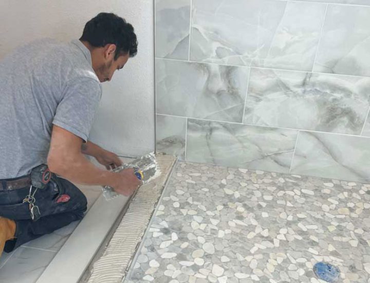 a man laying down tile adhesive on the floor